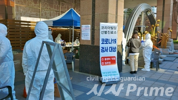 [시사프라임 / 박선진 기자] 한 입주민이 코리아빌딩 앞에 설치된 선별진료소 앞에서 검사에 대해 물어보고 있다.
