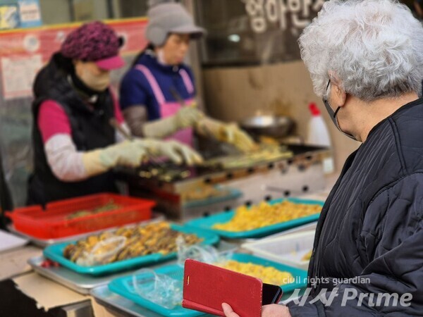 24.2.8. 한 시민이  차례상 올라갈 음식을 바라보고 있다 [사진=김종숙 기자]